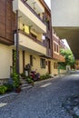 European narrow cobble-paved street between yellow classic houses in the old town. Small passage between buildings. Plants in pots Royalty Free Stock Photo