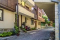 European narrow cobble-paved street between yellow houses in the old town. Small passage between brick buildings with flowers in Royalty Free Stock Photo