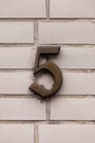 Number 5 germanic vintage antique metal house number on white tile wall