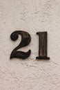 Number 21 painted black metal house number on white wall Royalty Free Stock Photo