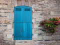 European old stone house facade with closed turquoise sun blinds window with flower pots