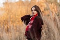 European pretty young woman fashion model in a stylish knitted sweater with a vintage checkered scarf posing outdoors in a field