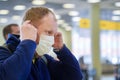 European redbeard man is in protective medical mask in airport.