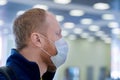 European redbeard man is in protective medical mask in airport.