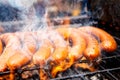 European sausages on grill. Flame and smoke. Royalty Free Stock Photo