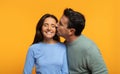 European senior affectionately husband kisses woman on cheek, both smiling with eyes closed
