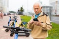 Senior man with smartphone activating electric scooter