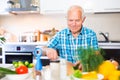 senor man preparing fresh vegetable salad at home in the kitchen Royalty Free Stock Photo