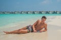 European sexy handsome man enjoying sun bath at tropical sandy beach at island luxury resort