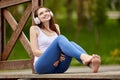 Smiling shoeless woman in cordless headphones listens to music in park.