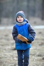 A European six-year-old boy in blue clothes carries firewood