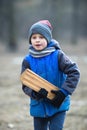 A European six-year-old boy in blue clothes carries firewood