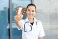 European smiling nurse in a white coat with a stethoscope showing to the camera several packages of pills Royalty Free Stock Photo