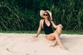 European with soft smooth skin rests on the beach, sunbathing and enjoying the sun, wears a stylish black swimsuit, hat Royalty Free Stock Photo
