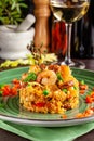 European Spanish cuisine. Paella with shrimps, chicken and coblas chorizo. White wine on the table. Closeup background image