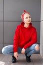 European stylish young blond woman in a fashionable red hooded sweatshirt in a vintage bandana in black boots in a blue jeans Royalty Free Stock Photo