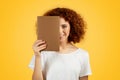 European teen woman hold book on yellow background