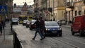 People passing by old Lviv city street with busy traffic