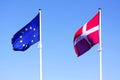 European Union EU and danish flag for Denmark on a pole waving in the wind with a blue sky on a sunny day