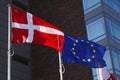 European Union EU and danish flag for Denmark on a pole waving in the wind with a blue sky on a sunny day