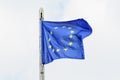 European Union flag blowing in the wind towards cloudy sky in a rainy ray Royalty Free Stock Photo