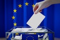 European Union flag, hand dropping ballot card into a box - voting, election concept Royalty Free Stock Photo