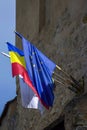 European Union flag and Romanian flag are fixed on facade of an ancient Rupea fortress against background of cloudy sky. Royalty Free Stock Photo