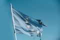 European union twelve star flag torn and with knots in wind on blue sky background. Flag is torn off at side, symbol of
