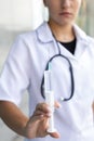 European white female intern with stethoscope in medical gown holding syringe up and spraying liquid from syringe close-up Royalty Free Stock Photo