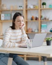 a European woman in her home office is working with a laptop or watching a webinar