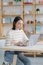 a European woman in her home office is working with a laptop or watching a webinar