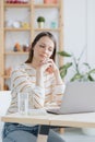 a European woman in her home office is working with a laptop or watching a webinar