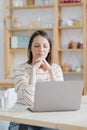 a European woman in her home office is working with a laptop or watching a webinar