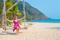 European woman, long-haired blonde in a bright dress swinging on a swing on the seashore. Travel and tourism in Asia