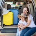 European woman sitting with her son in the trunk of an SUV. Beautiful happy mother loving hugs son. Yellow luggage for Royalty Free Stock Photo