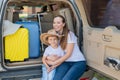 European woman sitting with her son in the trunk of an SUV. Beautiful happy mother loving hugs son. Yellow luggage for Royalty Free Stock Photo