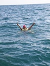 European woman staying afloat with cork lifesaving vest in open ocean and shows thumbs up