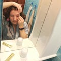 European woman tweeze eyebrows at bathroom