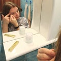 European woman tweeze eyebrows at bathroom