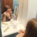 European woman tweeze eyebrows at bathroom