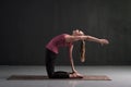 Woman yoga instructor doing advanced variation of camel pose or Ustrasana asana