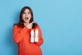 European young beautiful woman holding two blank bottles of milk or yogurt in hands while posing isolated on blue background Royalty Free Stock Photo