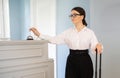 European Young Businesswoman Ringing Bell At Reception Counter Indoors