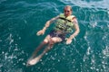 European young man staying afloat with cork lifesaving vest in open ocean