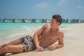 European young sexy handsome man enjoying sun bath at tropical sandy beach at island luxury resort