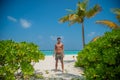 European young tanned man wearing swimming shorts at tropical beach at island luxury resort Royalty Free Stock Photo