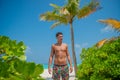 European young tanned sexy man wearing swimming shorts at tropical beach at island luxury resort Royalty Free Stock Photo