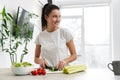 European young woman smiling and making salad in kitchen Royalty Free Stock Photo