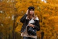 European young woman in stylish clothes in a vintage hat with a black leather bag posing in a park. Attractive trendy girl fashion Royalty Free Stock Photo