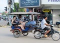 Europeans with cambodian tuk tuk driver on the street of asian city